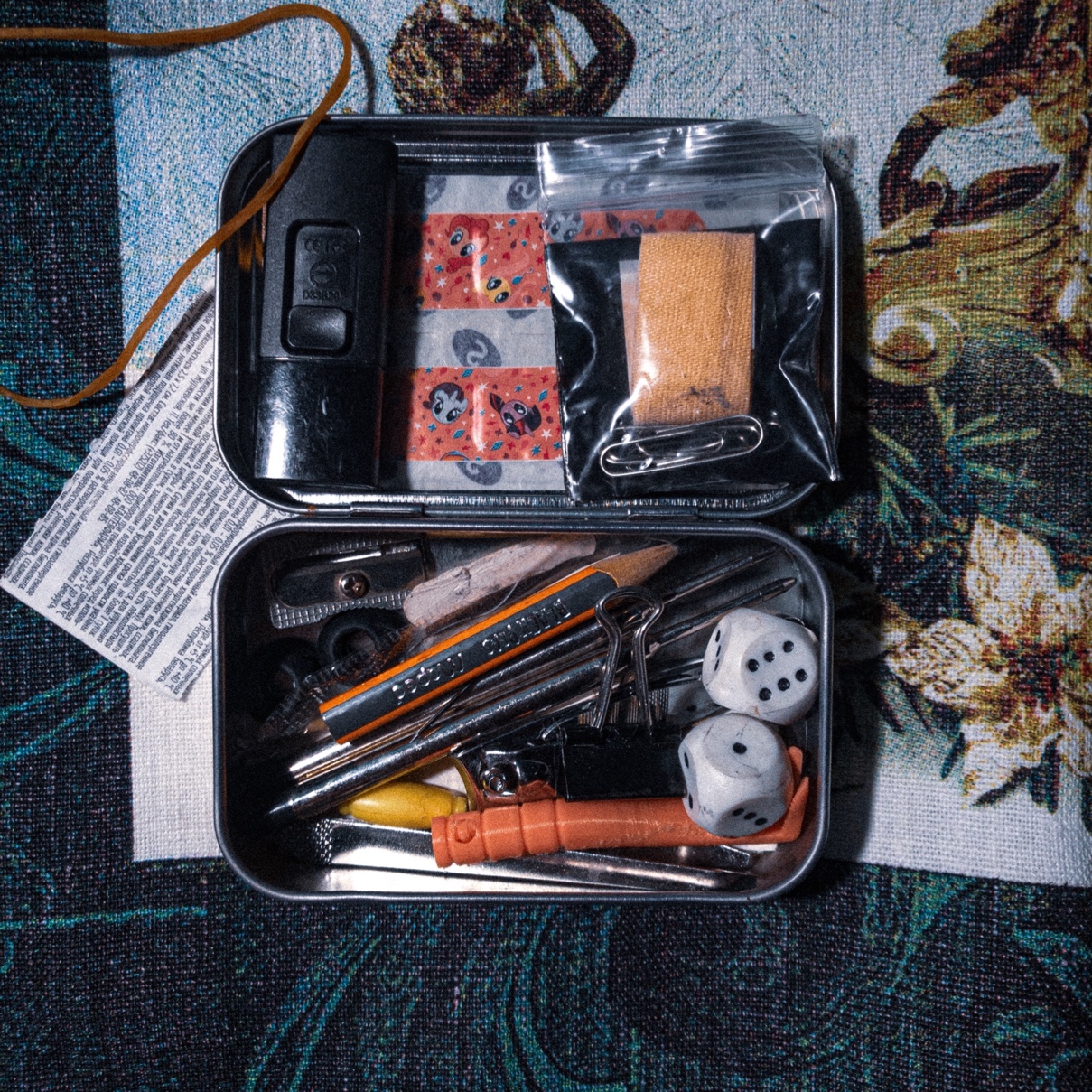 A mint tin containing various small items.